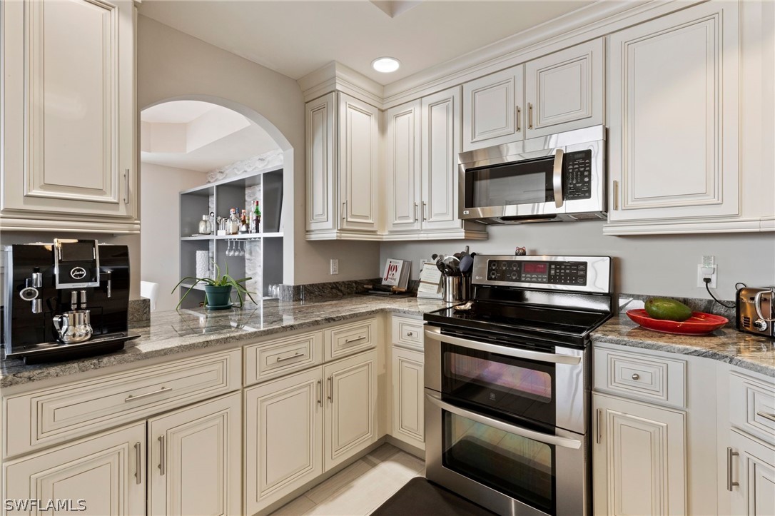 2104 West First Street, Unit 1404 Fort Myers, FL 33901 - Photo 17 of 30 a kitchen with stainless steel appliances granite countertop white cabinets and a stove