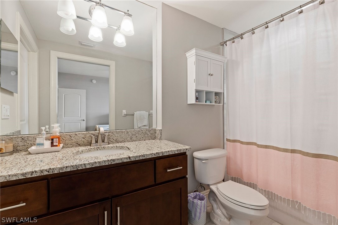 2104 West First Street, Unit 1404 Fort Myers, FL 33901 - Photo 25 of 30 a bathroom with a granite countertop sink a toilet and a mirror