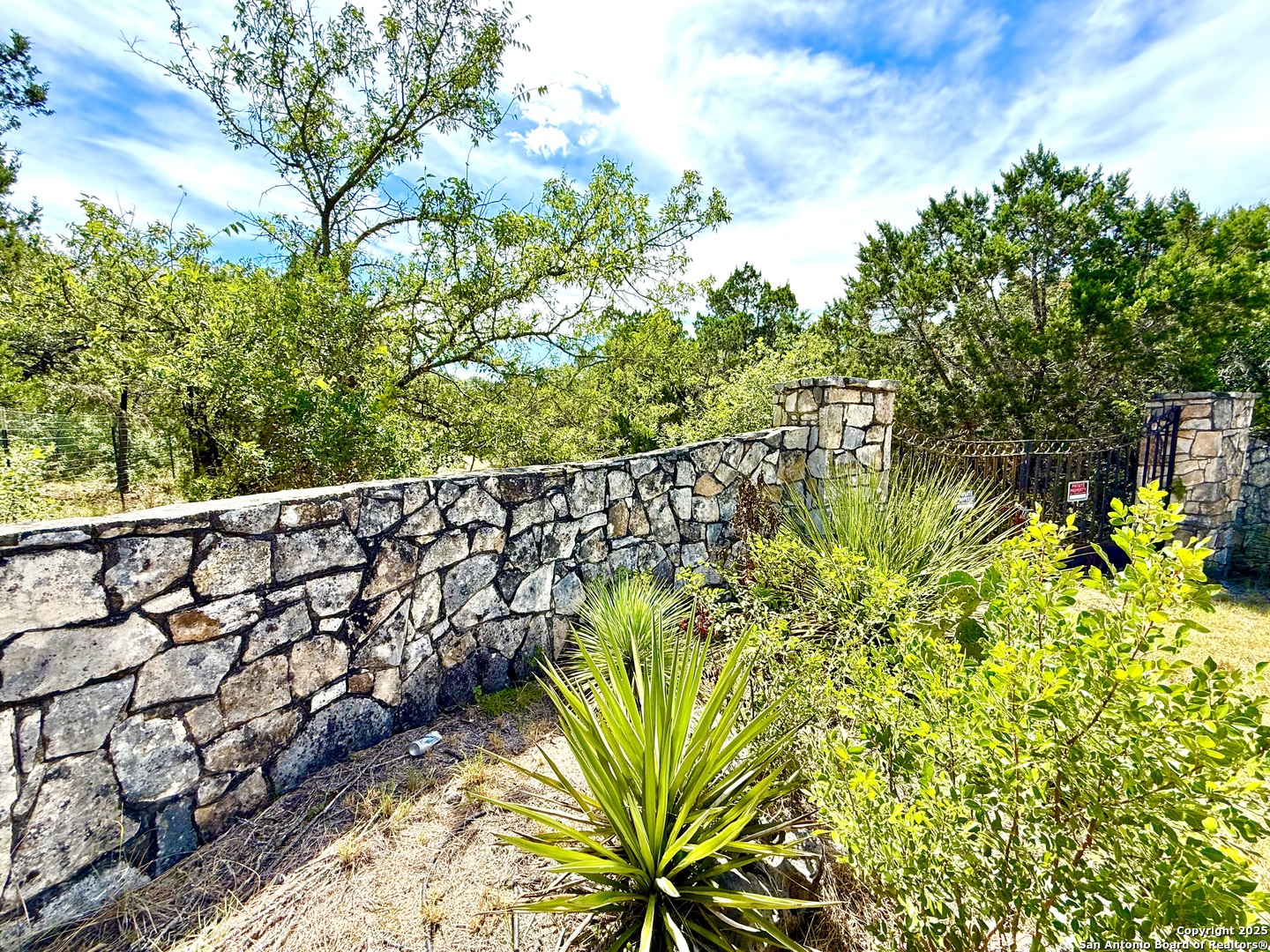 9852 Marnoch Road Helotes, TX 78023 - Photo 1 of 14 a view of a garden with plants and a bench