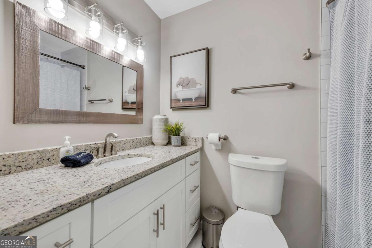 6805 Wright Road Northeast Atlanta, GA 30328 - Photo 15 of 28 a bathroom with a granite countertop toilet sink and mirror