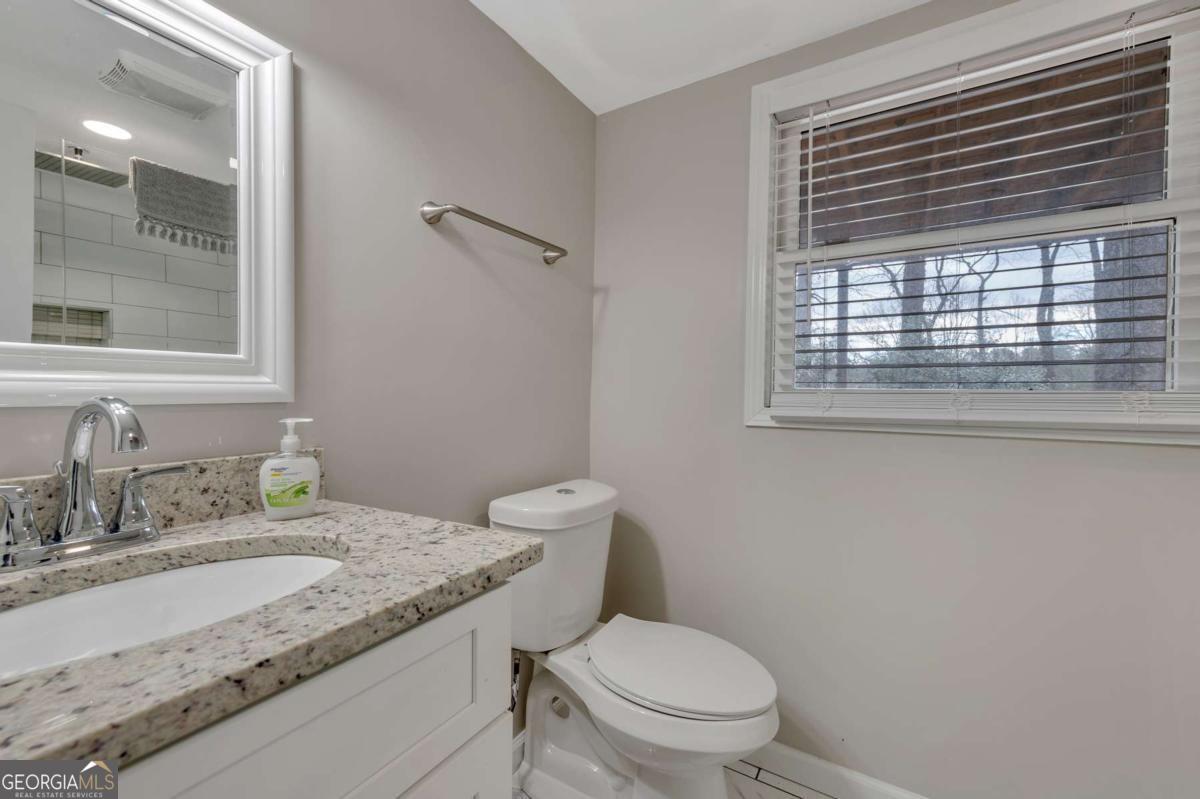 6805 Wright Road Northeast Atlanta, GA 30328 - Photo 26 of 28 a bathroom with a granite countertop toilet a sink and a window