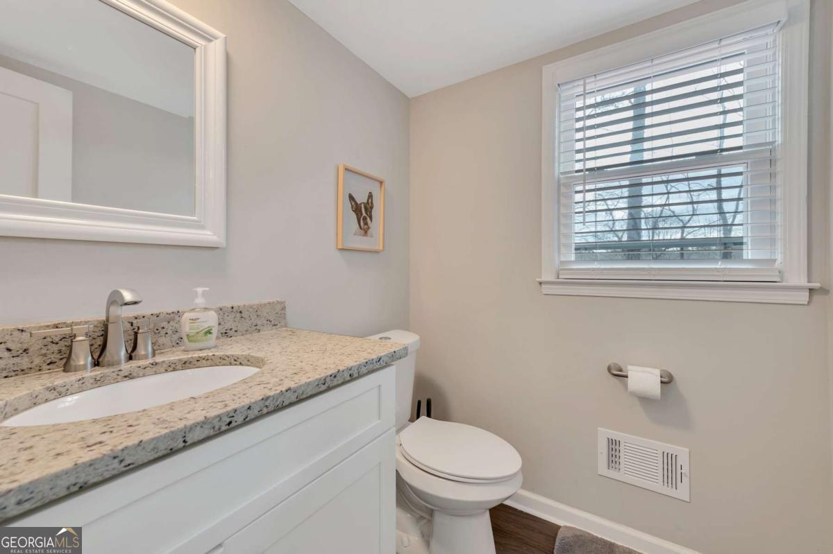 6805 Wright Road Northeast Atlanta, GA 30328 - Photo 6 of 28 a bathroom with a granite countertop sink toilet and a window