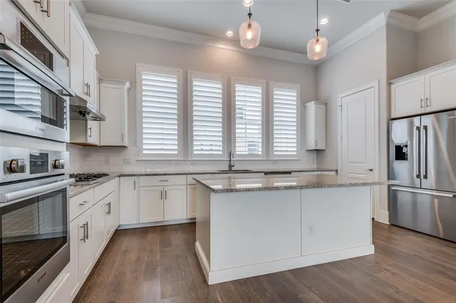 a kitchen with stainless steel appliances granite countertop hardwood floor sink stove and wooden cabinets