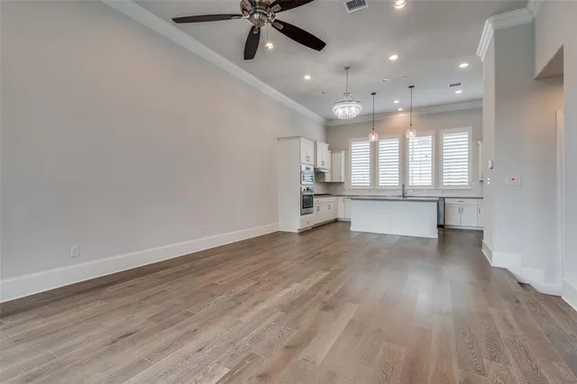an empty room with wooden floor a ceiling fan and windows