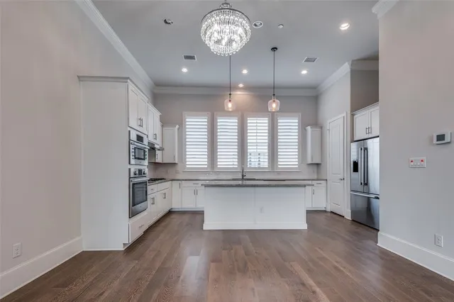 a large kitchen with cabinets wooden floor and stainless steel appliances