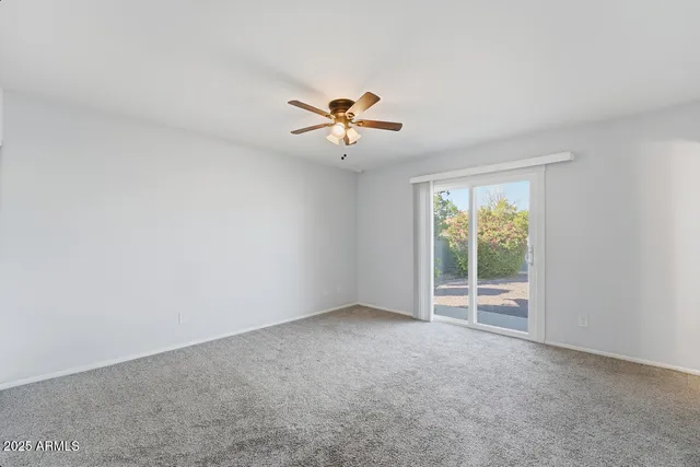 an empty room with a window and a ceiling fan