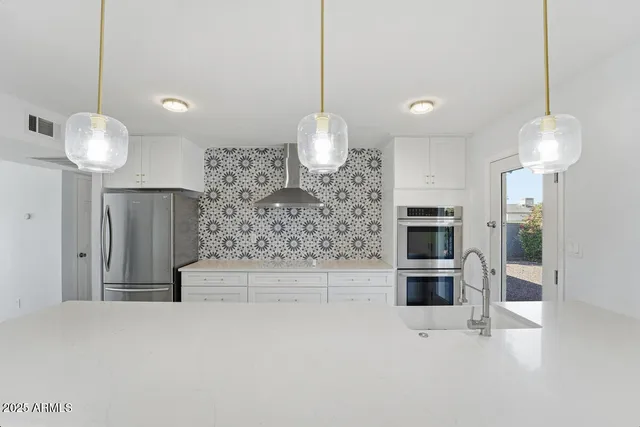 a large kitchen with stainless steel appliances a refrigerator and a sink