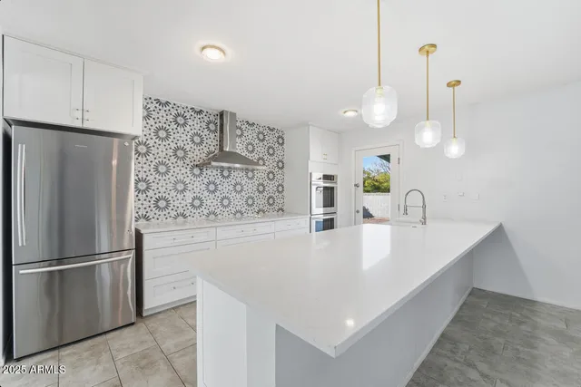 a large white room with kitchen area and wooden floor
