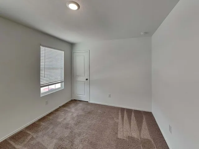 a view of an empty room with a window and closet area