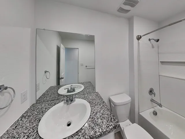 a bathroom with a granite countertop sink mirror vanity and toilet