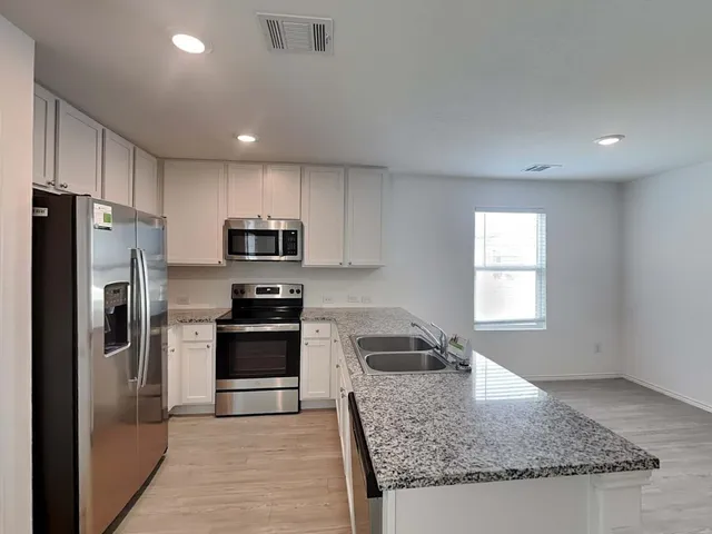 a kitchen with granite countertop kitchen island stainless steel appliances a refrigerator sink stove microwave and cabinets