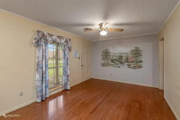 an empty room with wooden floor chandelier and windows