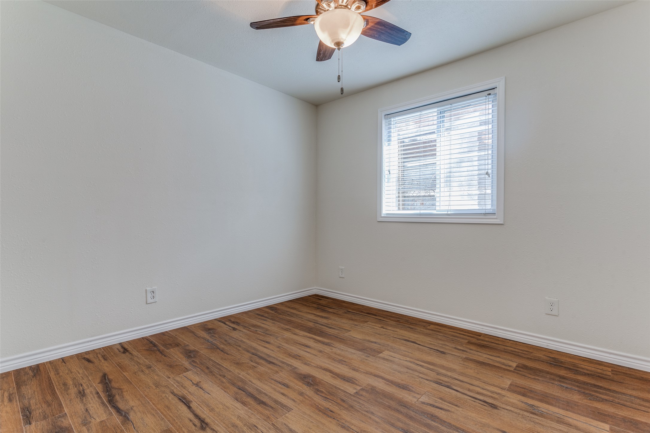 2401 Manor Road, Unit 113 Austin, TX 78722 - Photo 11 of 12 Empty room featuring ceiling fan, wood finished floors, and baseboards