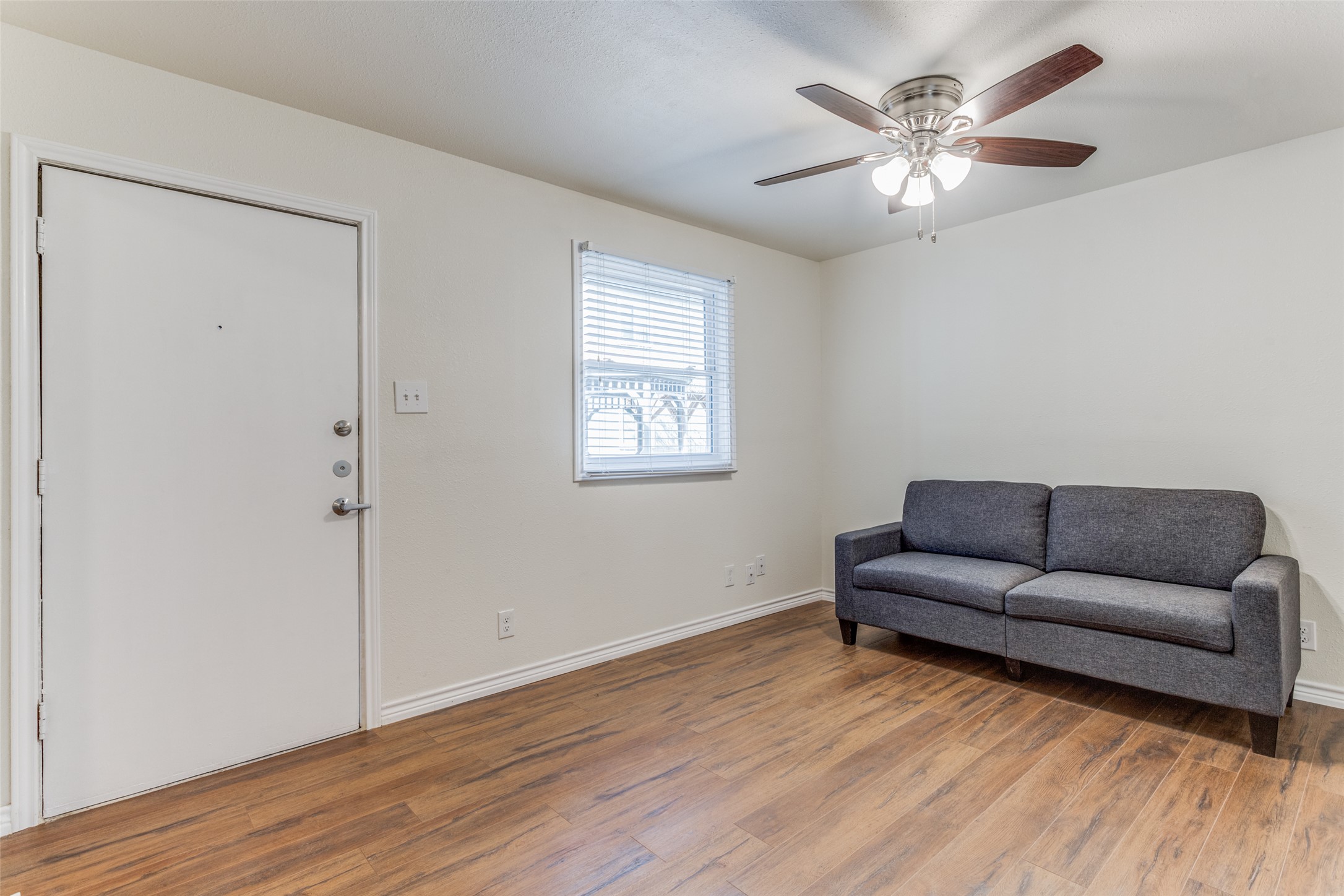 2401 Manor Road, Unit 113 Austin, TX 78722 - Photo 2 of 12 Living area featuring wood finished floors, a ceiling fan, and baseboards