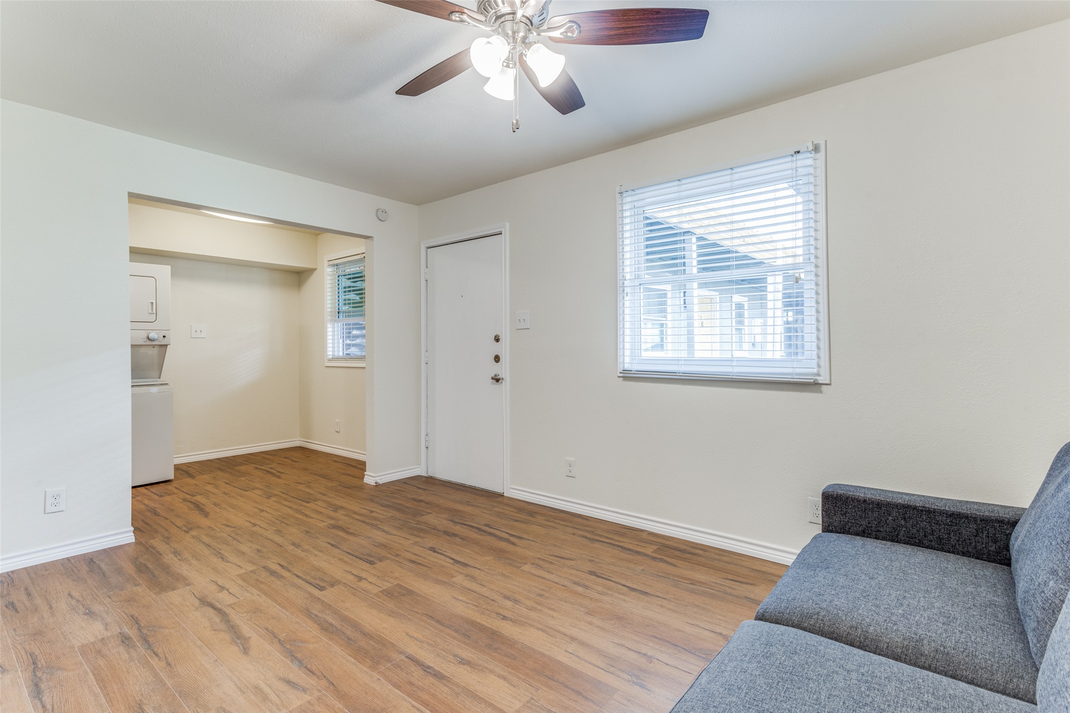 2401 Manor Road, Unit 113 Austin, TX 78722 - Photo 4 of 12 Living area featuring stacked washer and clothes dryer, light wood finished floors, baseboards, and ceiling fan