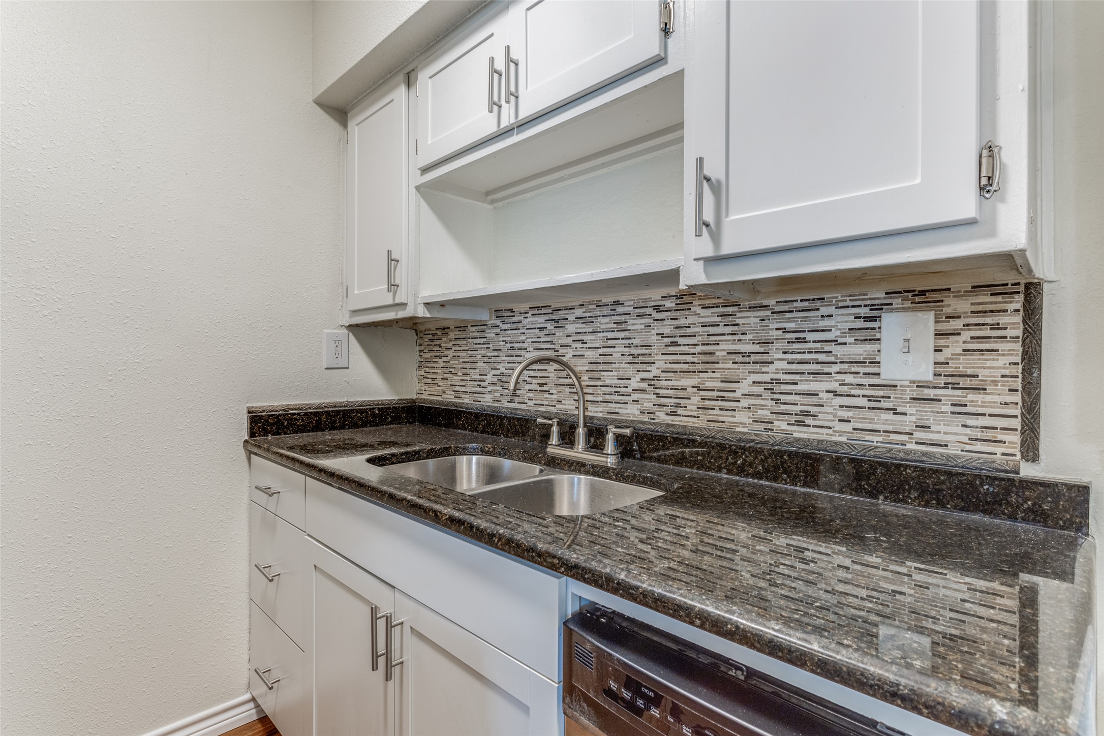2401 Manor Road, Unit 113 Austin, TX 78722 - Photo 7 of 12 Kitchen with a sink, tasteful backsplash, white cabinetry, dark stone countertops, and dishwasher