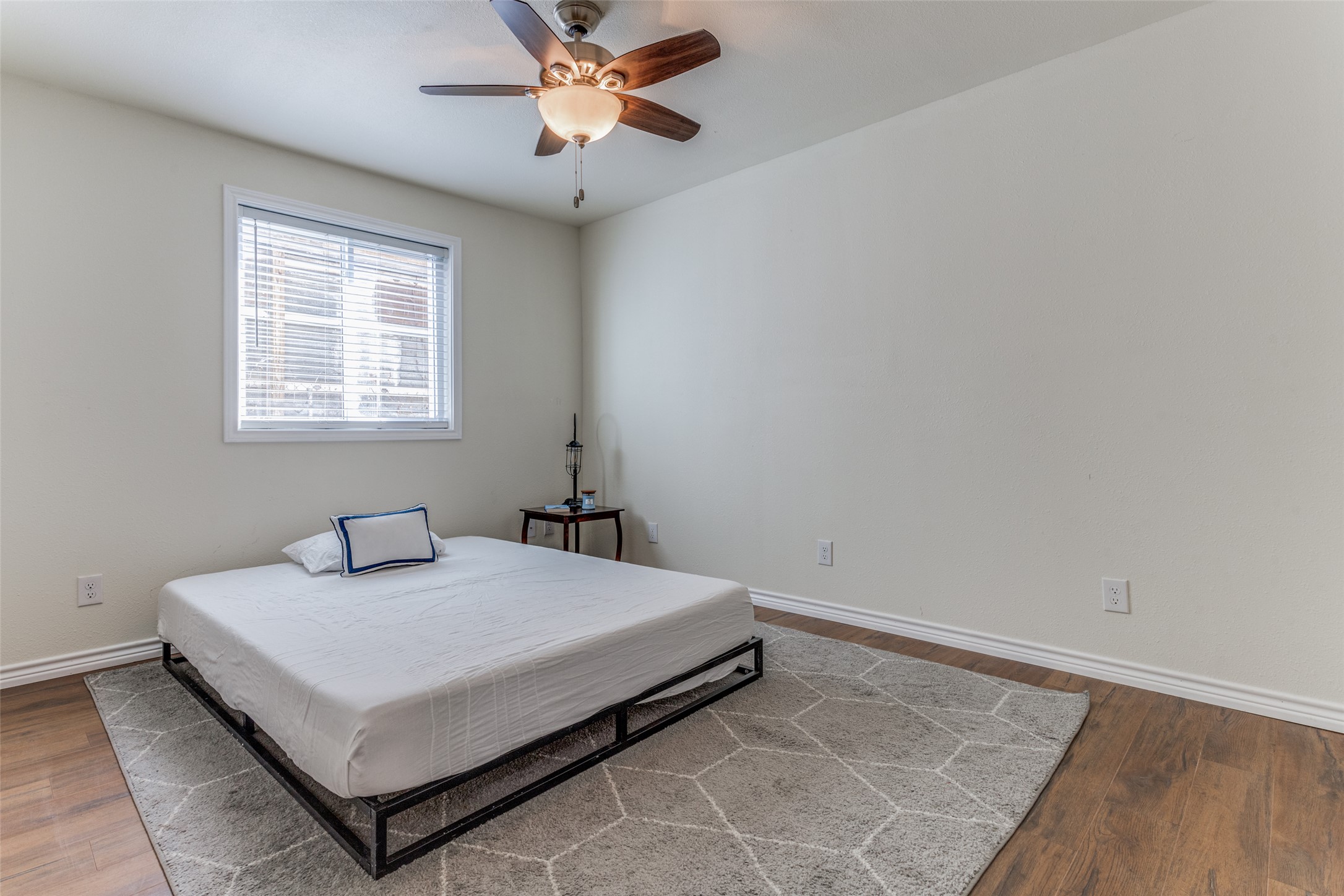 2401 Manor Road, Unit 113 Austin, TX 78722 - Photo 10 of 12 Bedroom with baseboards, wood finished floors, and a ceiling fan