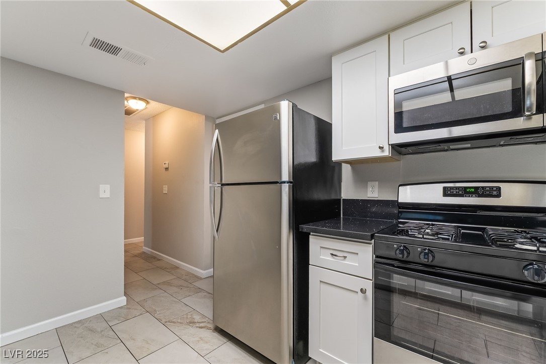 2755 Carnation Lane Henderson, NV 89074 - Photo 11 of 42 Kitchen featuring appliances with stainless steel finishes, white cabinetry, and dark stone countertops