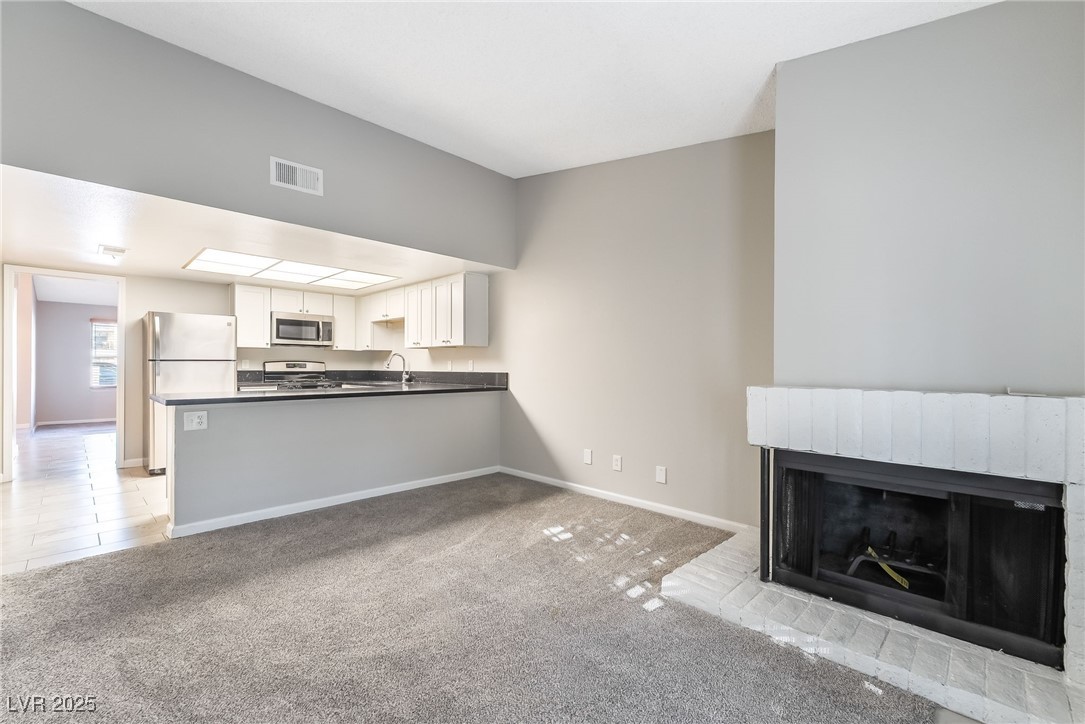 2755 Carnation Lane Henderson, NV 89074 - Photo 14 of 42 Unfurnished living room featuring light carpet, light tile patterned floors, and a fireplace