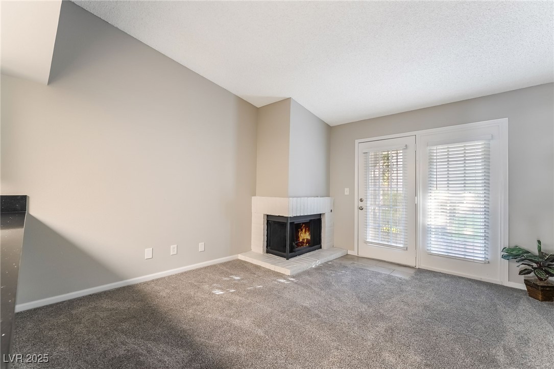 2755 Carnation Lane Henderson, NV 89074 - Photo 17 of 42 Unfurnished living room featuring a multi sided fireplace, carpet, and a textured ceiling