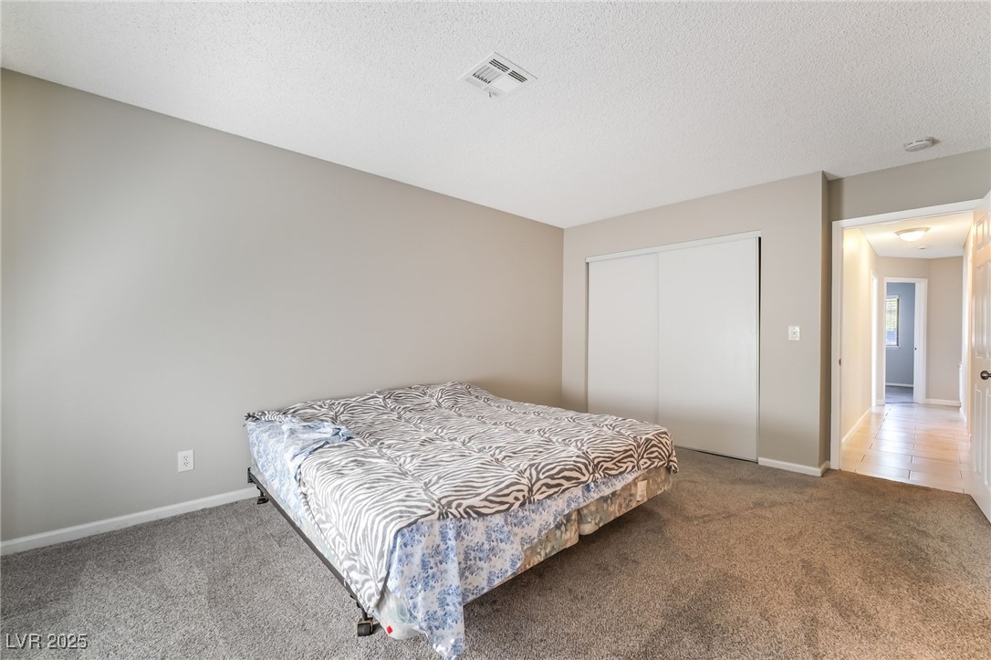 2755 Carnation Lane Henderson, NV 89074 - Photo 22 of 42 Bedroom with carpet flooring, a textured ceiling, and a closet