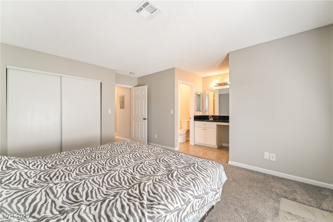 2755 Carnation Lane Henderson, NV 89074 - Photo 23 of 42 Bedroom featuring a closet, ensuite bath, and light colored carpet