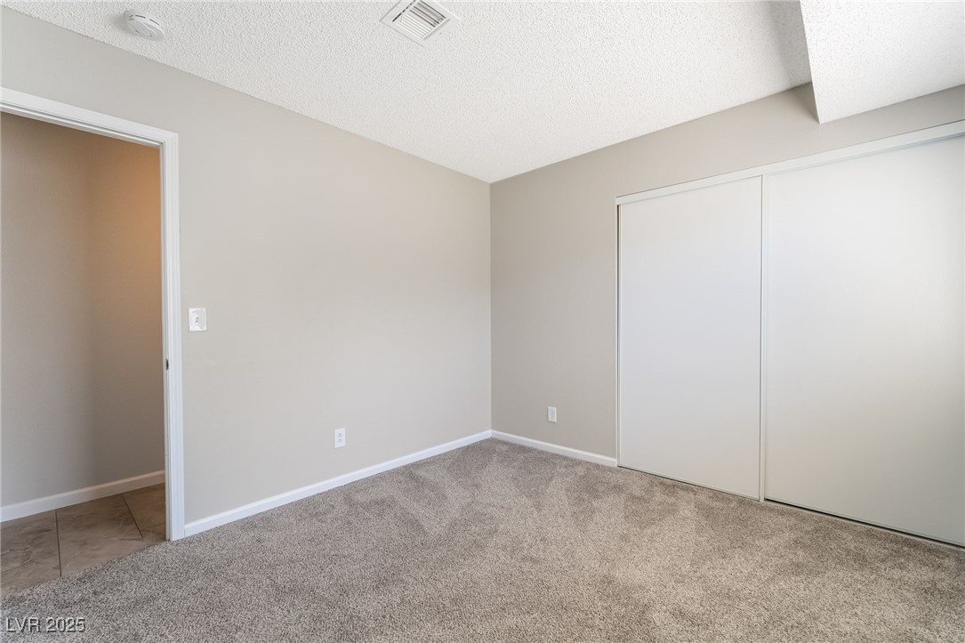 2755 Carnation Lane Henderson, NV 89074 - Photo 31 of 42 Unfurnished bedroom with light colored carpet, a textured ceiling, and a closet