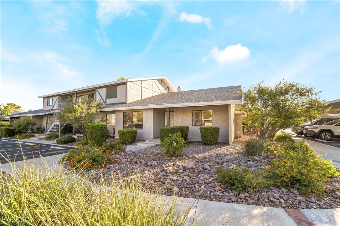2755 Carnation Lane Henderson, NV 89074 - Photo 41 of 42 View of front of house featuring stucco siding, a shingled roof, stairway, a porch, and a chimney