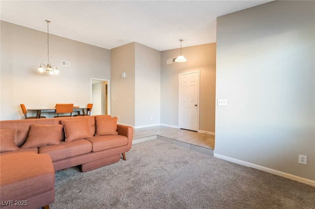 2755 Carnation Lane Henderson, NV 89074 - Photo 6 of 42 Carpeted living room with a chandelier and baseboards