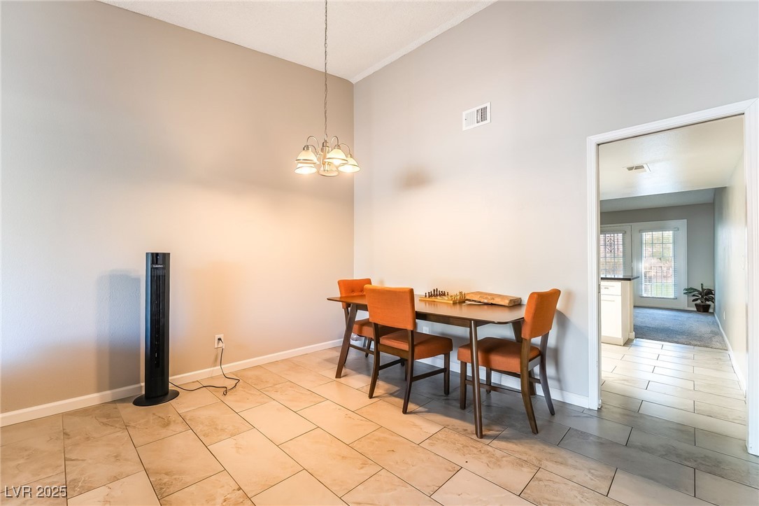 2755 Carnation Lane Henderson, NV 89074 - Photo 7 of 42 Dining area featuring a chandelier, a high ceiling, and light tile patterned floors