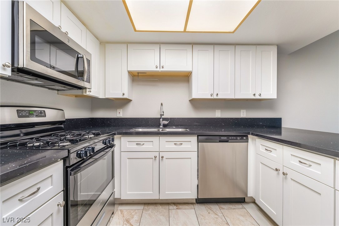 2755 Carnation Lane Henderson, NV 89074 - Photo 10 of 42 Kitchen featuring stainless steel appliances, white cabinetry, and dark stone countertops