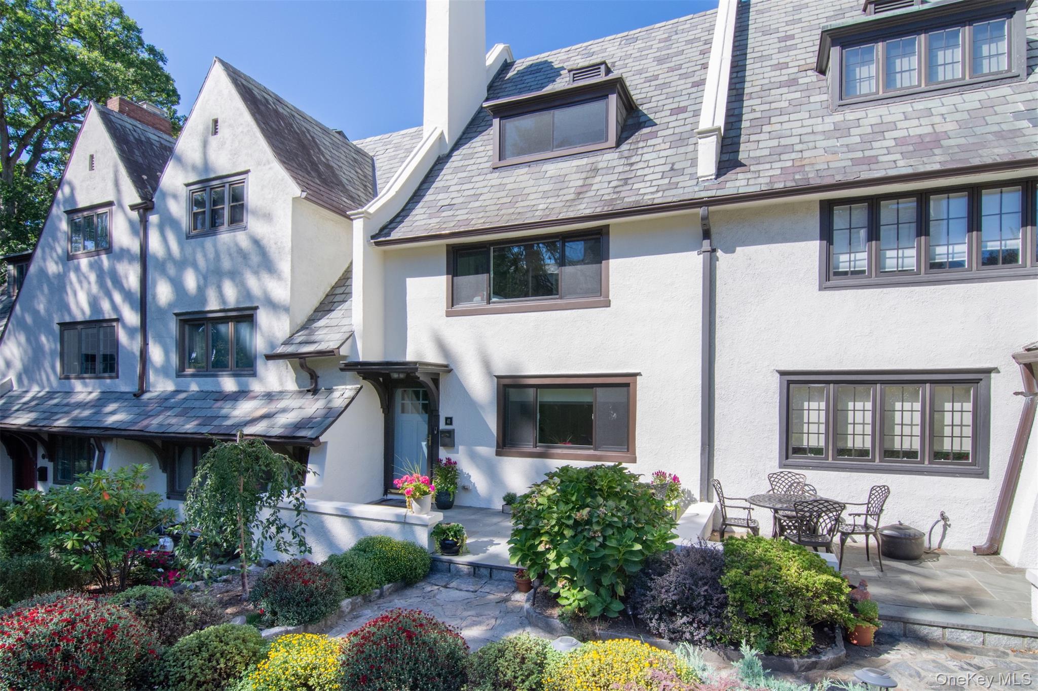 41 Sagamore Road Bronxville, NY 10708 - Photo 2 of 38 Front of home with mature landscaping, slate roof, new windows, stucco siding, and chimney