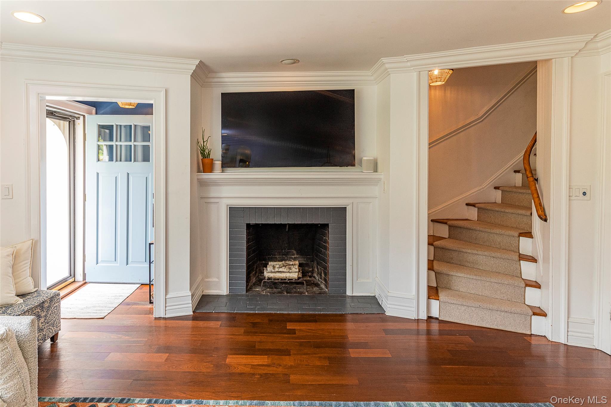 41 Sagamore Road Bronxville, NY 10708 - Photo 5 of 38 Entryway to living room with recessed lighting, stairway, ornamental molding, hardwood flooring, and wood burning fireplace with flush hearth