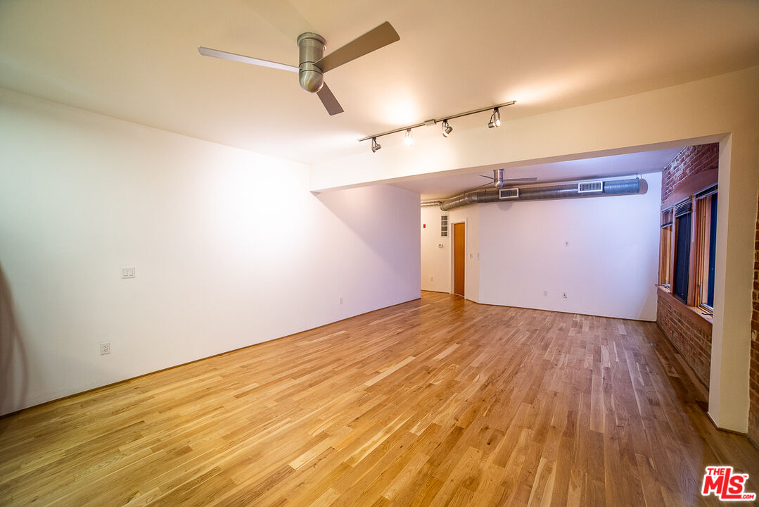 a view of empty room with wooden floor and fan