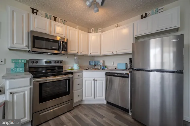 a kitchen with stainless steel appliances white cabinets white stove a refrigerator and a microwave
