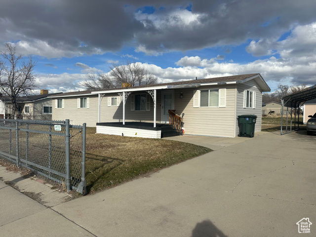 451 American Way Tooele, UT 84074 - Photo 1 of 1 View of front of home featuring a carport, covered porch, concrete driveway, and fence