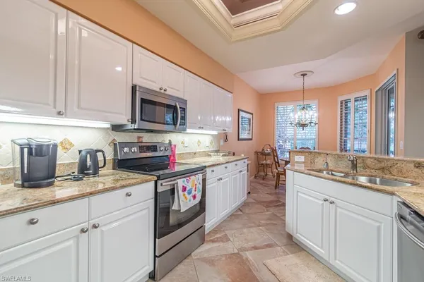 a kitchen with granite countertop a sink stainless steel appliances and white cabinets