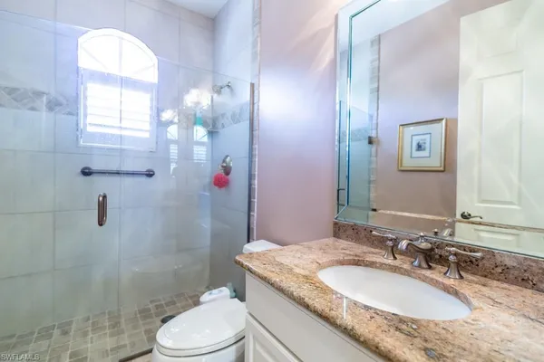 a bathroom with a granite countertop sink toilet a mirror and shower