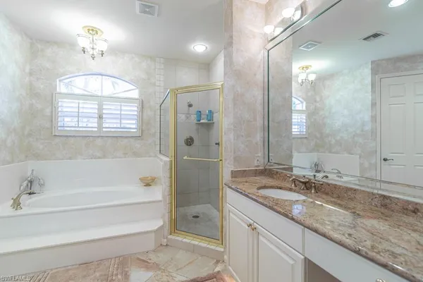 a bathroom with a granite countertop tub sink shower and mirror