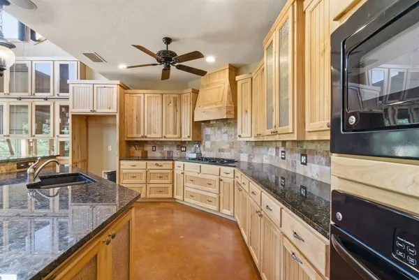 a kitchen with stainless steel appliances granite countertop a sink a stove and a wooden floors