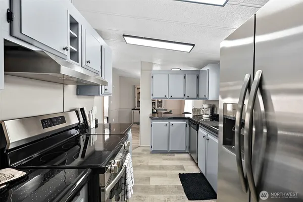 a kitchen with stainless steel appliances kitchen island granite countertop a stove a refrigerator and a sink