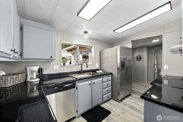 a kitchen with granite countertop a sink cabinets and stainless steel appliances