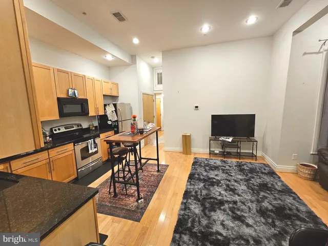 a living room with furniture a flat screen tv and a refrigerator