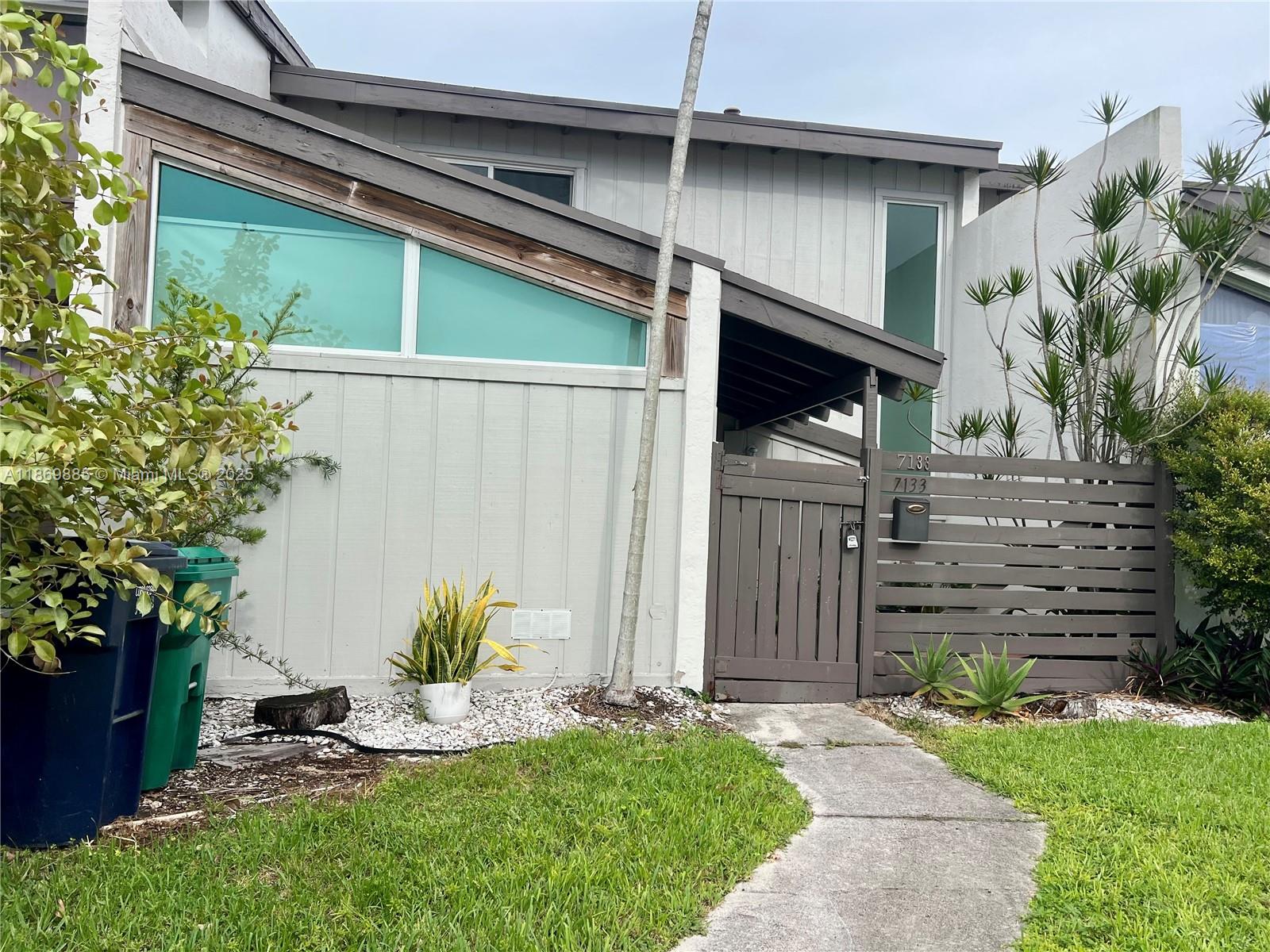 Snapper Creek Townhouses Miami, FL 33173 - Photo 19 of 20 a backyard of a house with potted plants and a bench