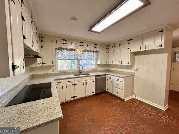 a kitchen with granite countertop a sink stainless steel appliances and white cabinets
