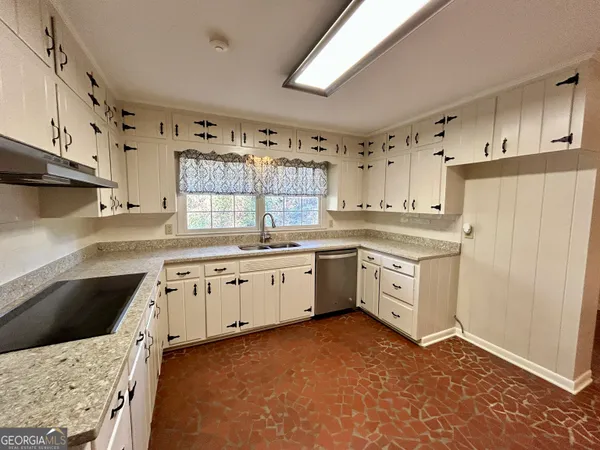 a kitchen with granite countertop a sink a stove a refrigerator and white cabinets