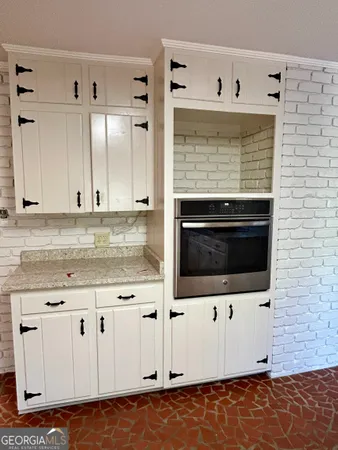 a kitchen with granite countertop white cabinets and white appliances
