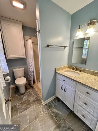 a bathroom with a granite countertop sink toilet and shower