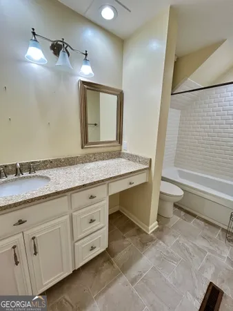 a bathroom with a granite countertop sink a toilet and mirror