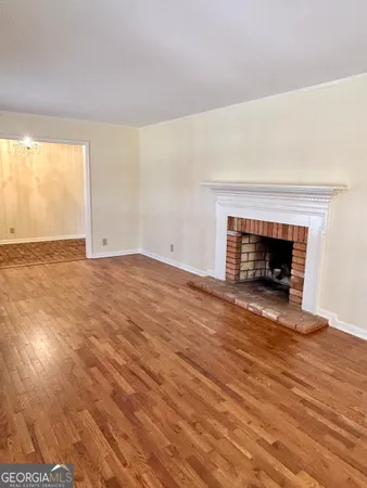 an empty room with wooden floor fireplace and windows